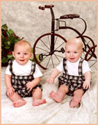 Twin baby boys in front of antique bicycle
